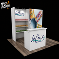 Backlit exhibit booth with white counter and La Croix can shelves under a hanging panel
